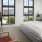 Model bedroom at our apartments for rent in Dallas, TX, featuring carpeted flooring and windows with a view of the city.